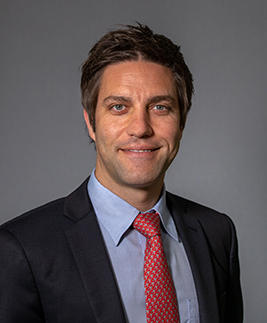 Portrait of Dr. Dan Raper smiling against a grey background.