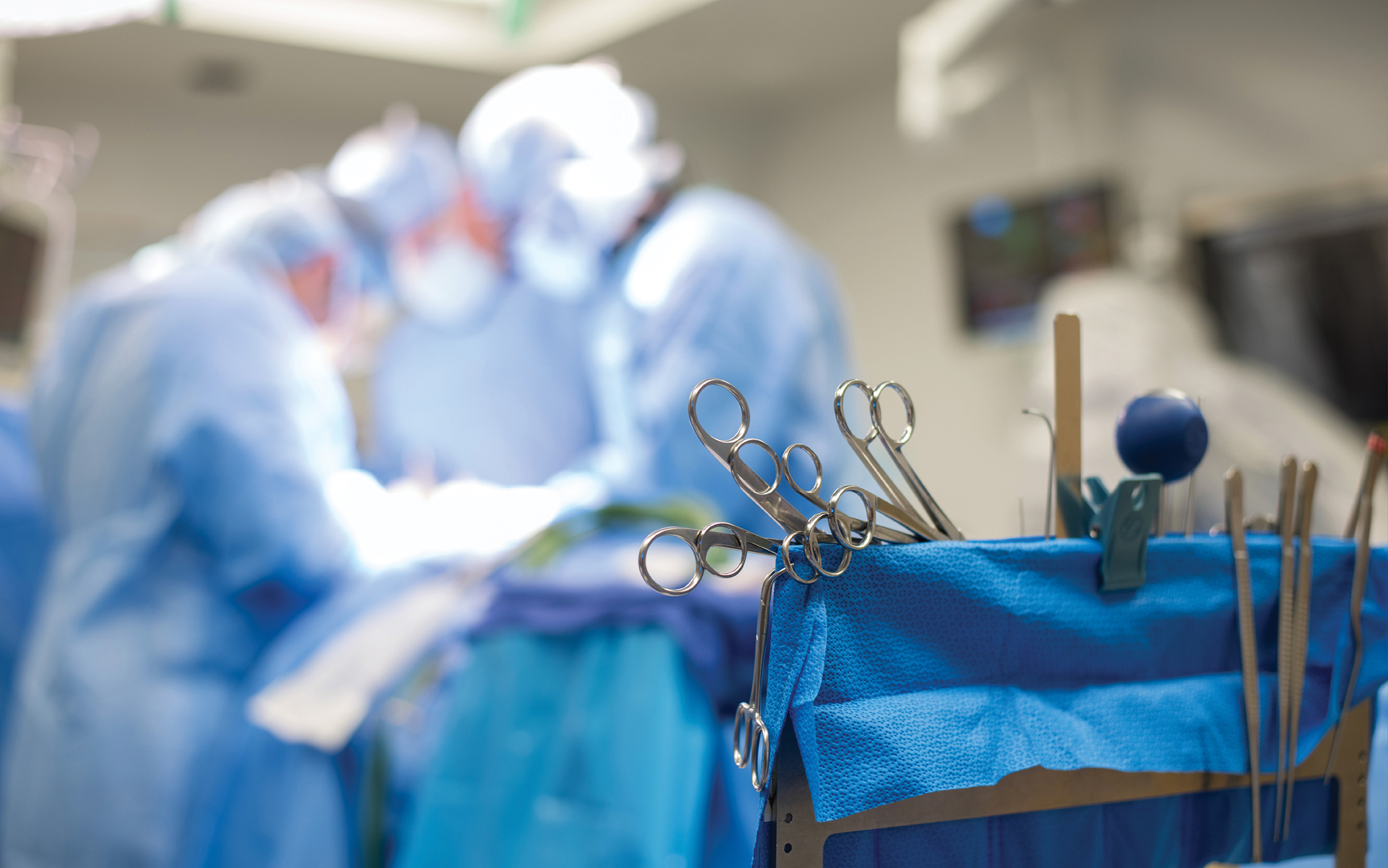 closeup of surgical tools with OR doctors and staff in background